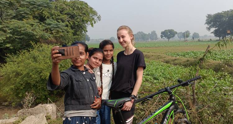 Turista tomándose una selfie con niños locales en un entorno rural.