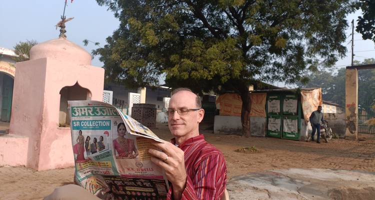 Hombre leyendo un periódico en un entorno al aire libre.