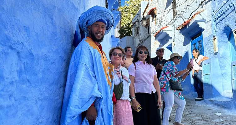 Gruppe von Menschen, die durch eine blaue Gasse mit einem Einheimischen in traditioneller Kleidung geht.