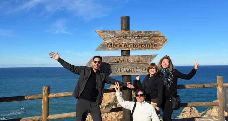 Quatre personnes posant devant un panneau au bord de mer.