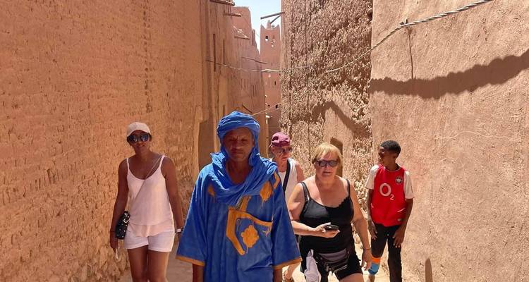 Des personnes marchant dans une rue étroite en tenue traditionnelle.