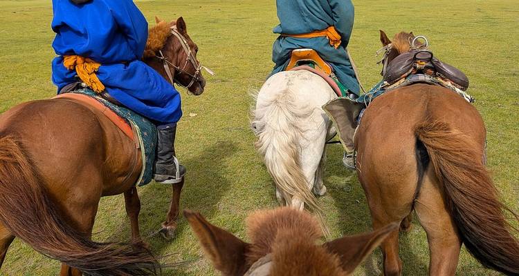 Tres personas a caballo en una zona de hierba.