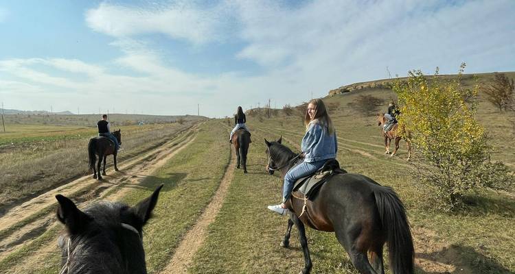 Personas montando a caballo a través de un paisaje montañoso.