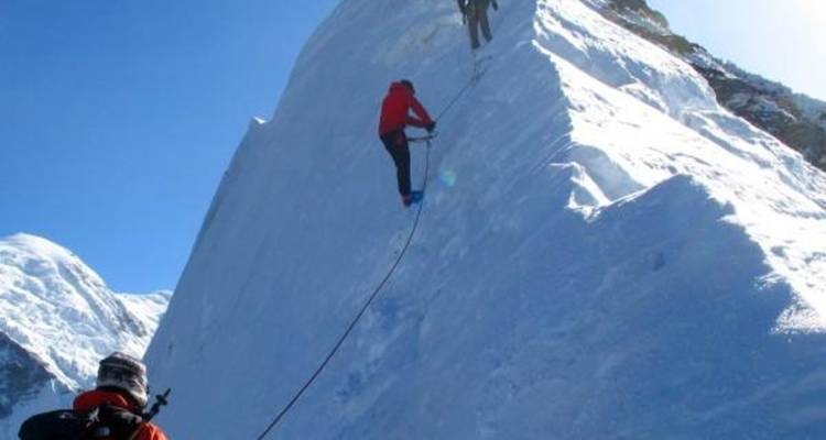 Climbers ascending a steep snowy ridge.