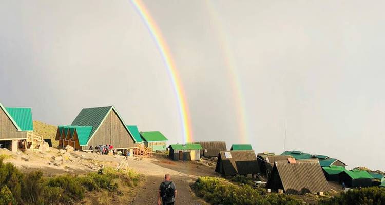 Campingplatz mit Gebäuden unter einem Doppelregenbogen.