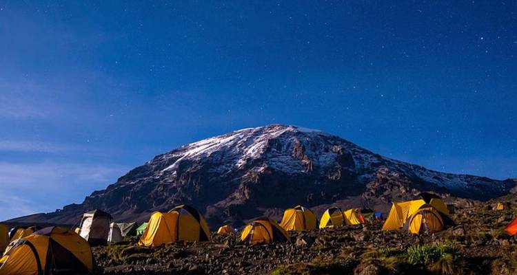 Campingplatz mit Bergen und Nachthimmel mit Sternen.