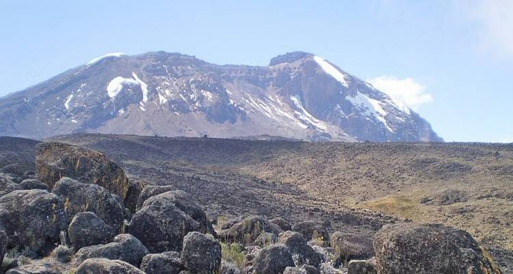 Vista expansiva de un paisaje rocoso con el Kilimanjaro en la distancia.