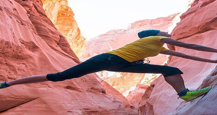 Persona escalando en un desfiladero rocoso y estrecho.