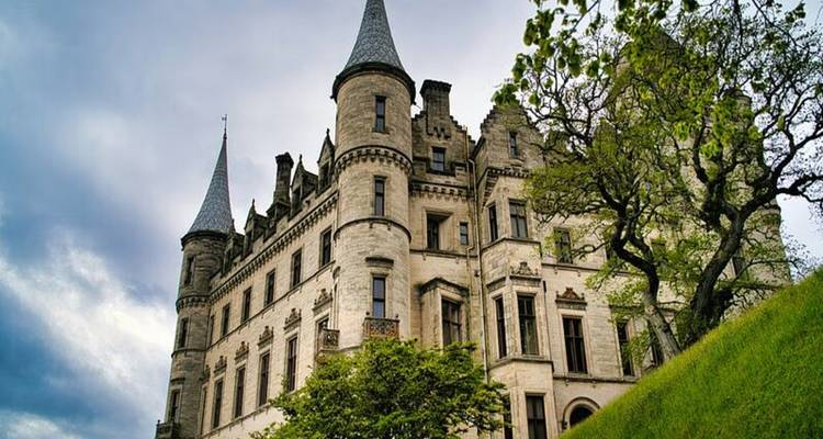 Historic castle with towers in a lush setting.