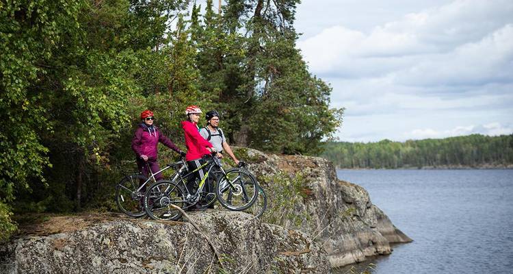 Des cyclistes sur un affleurement rocheux surplombant un lac.