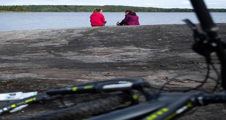 Vélo au sol avec deux personnes assises près d'un lac.