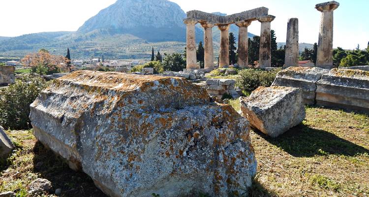 Oude stenen ruïnes met kolomstompen voor de hoge berg Akrokorinthe.