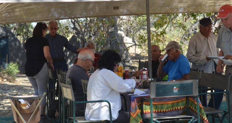 Groep mensen die buiten eten op een kampeerterrein.