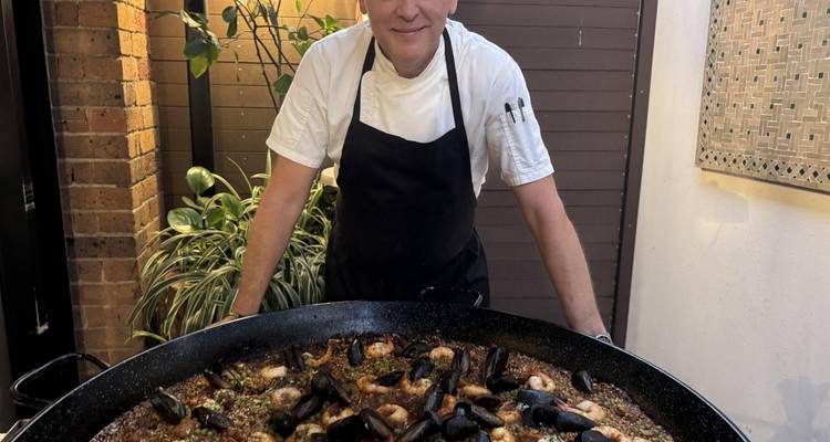 Chef die een grote pan paella presenteert