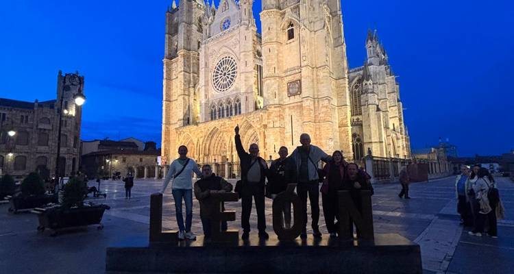 Viajeros silueteados en el letrero de LEON con la Catedral de León iluminada en la hora azul