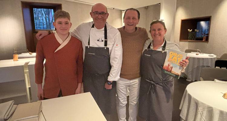 Invitados posando con chefs dentro de una cocina moderna de restaurante
