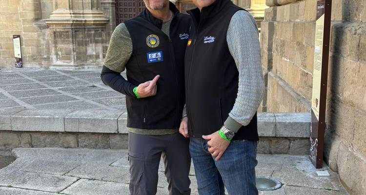 Dos peregrinos posando afuera de una iglesia histórica de piedra