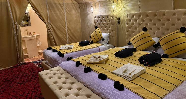 Luxurious tent interior with two beds and decorative pillows.