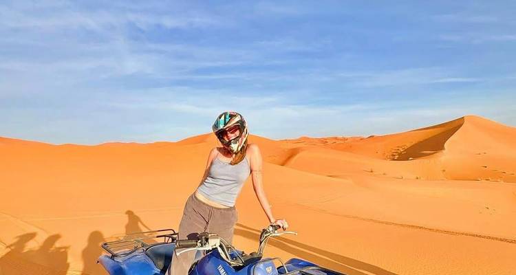 Personne sur un VTT bleu dans le désert avec des dunes de sable derrière.