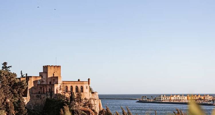 Coastal view with a historic building overlooking the ocean, clear sky.