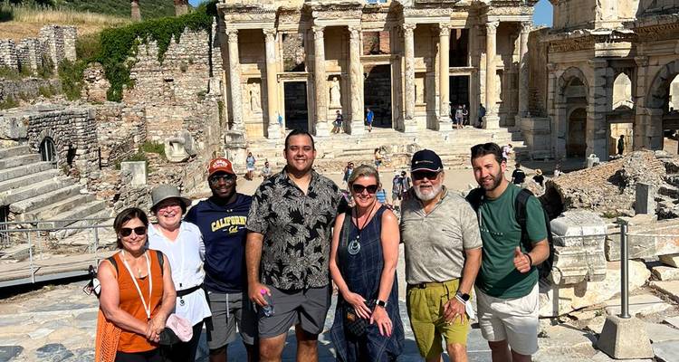 Tourists posing in front of ancient ruins on a sunny day.