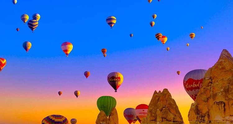 Hot air balloons floating over Cappadocia at sunrise.