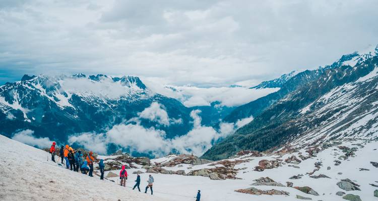 Grupo de excursionistas en montañas nevadas con vistas panorámicas.