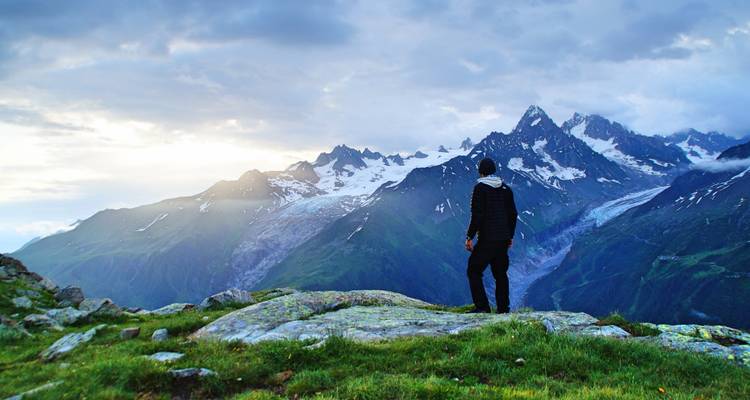 Persona de pie en una cresta montañosa con el Mont Blanc de fondo.
