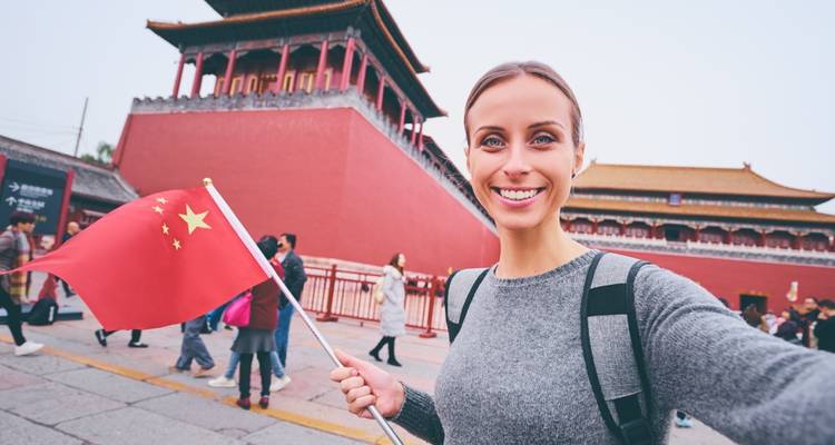 Personne tenant un drapeau devant un bâtiment chinois historique.