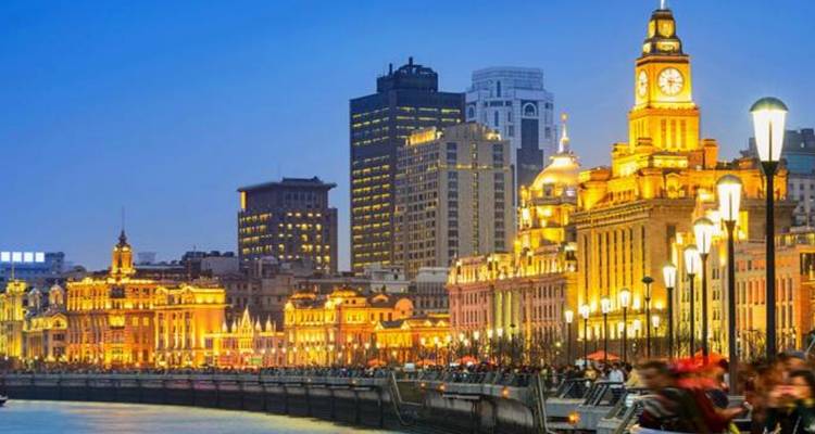 Bund illuminé au bord de l'eau avec des bâtiments historiques et une rivière.