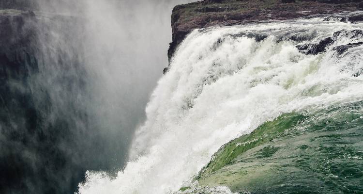 Nahaufnahme des Randes der Victoriafälle mit fließendem Wasser.