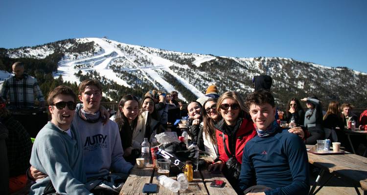 Group of people enjoying drinks with snowy mountains in the background.