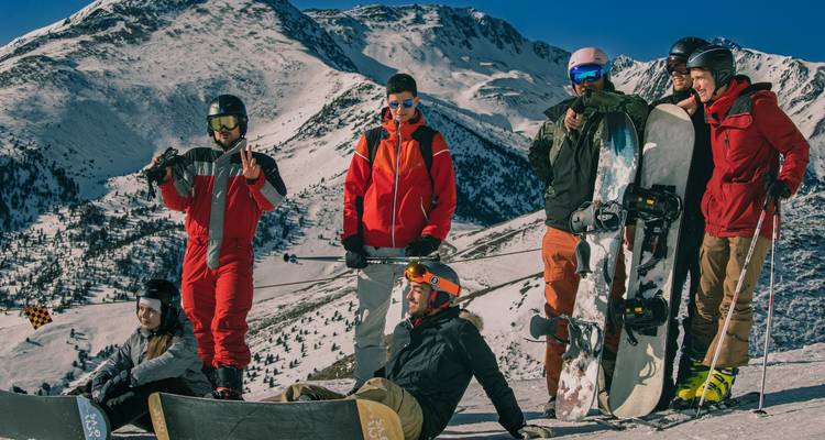 Group of friends with snowboards and a scenic mountain view.