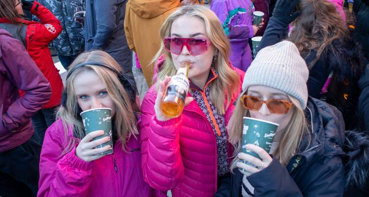 Three women enjoying drinks in winter attire.