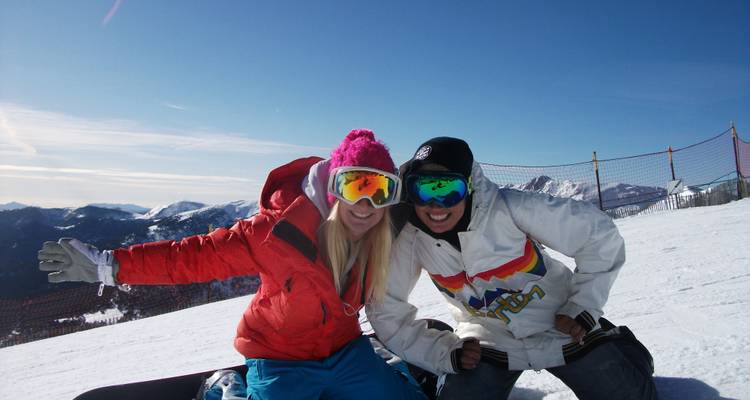 Two friends posing with snowboards on a snowy mountain.