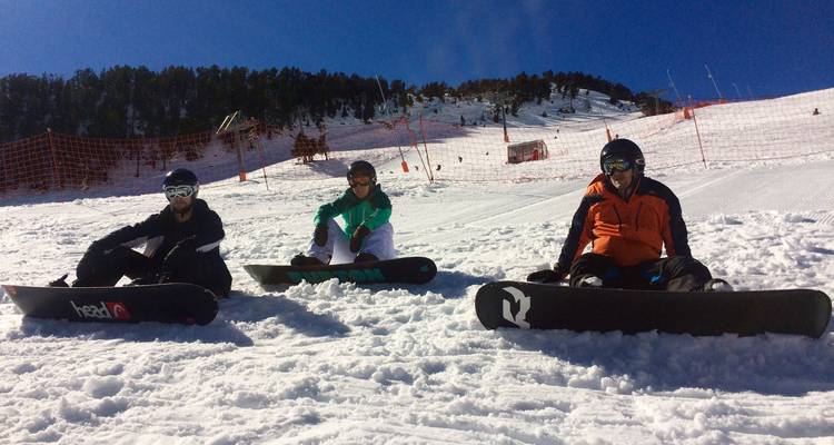 Three snowboarders sitting on the snowy ground.