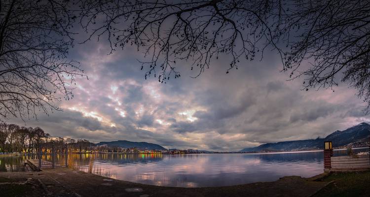 Panoramic view of a tranquil lake with surrounding mountains.