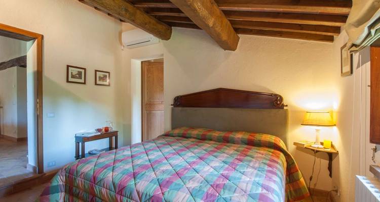 Chambre avec courtepointe colorée et poutres en bois.