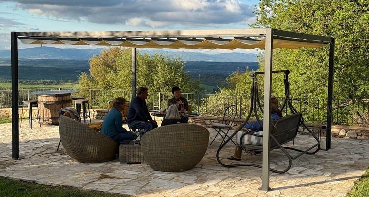 Des personnes se détendant sous une pergola avec vue sur la campagne.