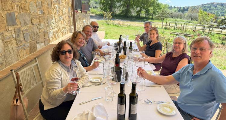 Groupe de personnes savourant un repas en plein air avec des bouteilles de vin sur la table.