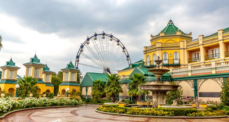 Edificios amarillos lujosos y plaza bordeada de palmeras con noria en Gold Reef City en Johannesburgo.