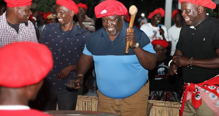 Groupe de personnes pratiquant une danse traditionnelle, portant des chapeaux rouges et des tenues colorées.