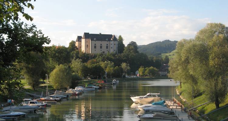 Río con barcas y castillo lejano en una colina