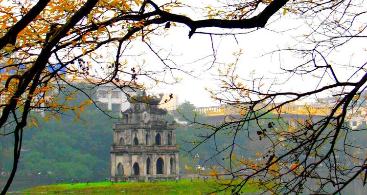 Tour emblématique entourée d'un lac et de feuilles d'automne.