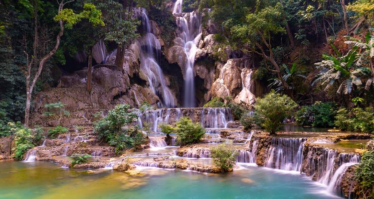 Belle cascade d'eau dégringolant sur des rochers dans un cadre forestier.