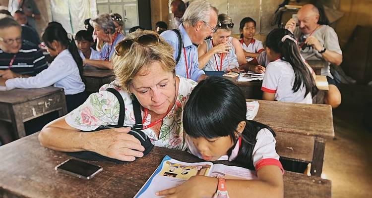 Femme âgée et enfant lisant un livre dans une salle de classe.