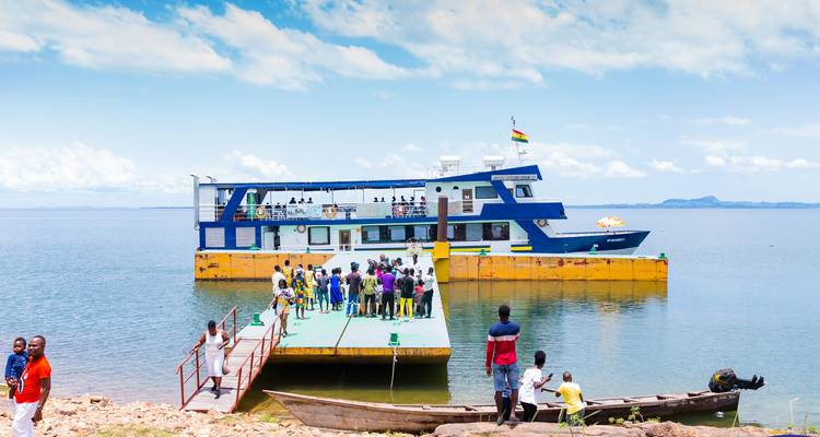 Grupo de personas abordando un barco en un muelle junto al lago.