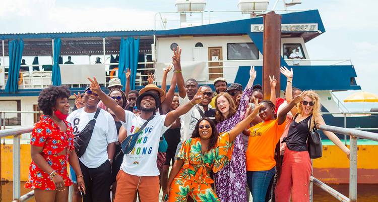 Un grupo alegre posando en un muelle con un barco de fondo.