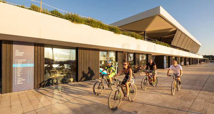 Groep fietsers die een modern jachthaven gebouw passeert.