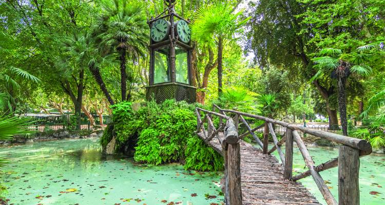 Ein ruhiger Park mit üppigem Grün und einem Uhrenturm.